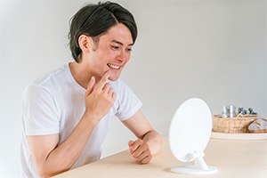 A man looking at his tooth in a mirror