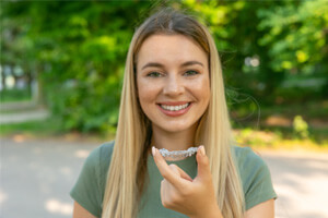 a teenager putting Invisalign aligners in her mouth