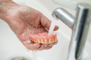 a person rinsing their denture